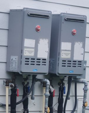 2 tankless water heaters mounted on the side of the house next to each other.